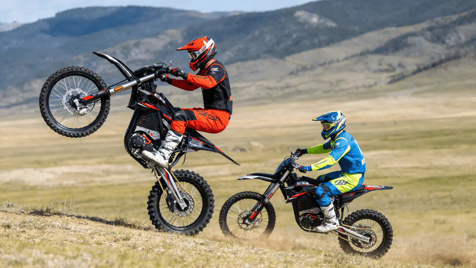 Two riders were riding off-road motorcycles across the grass.