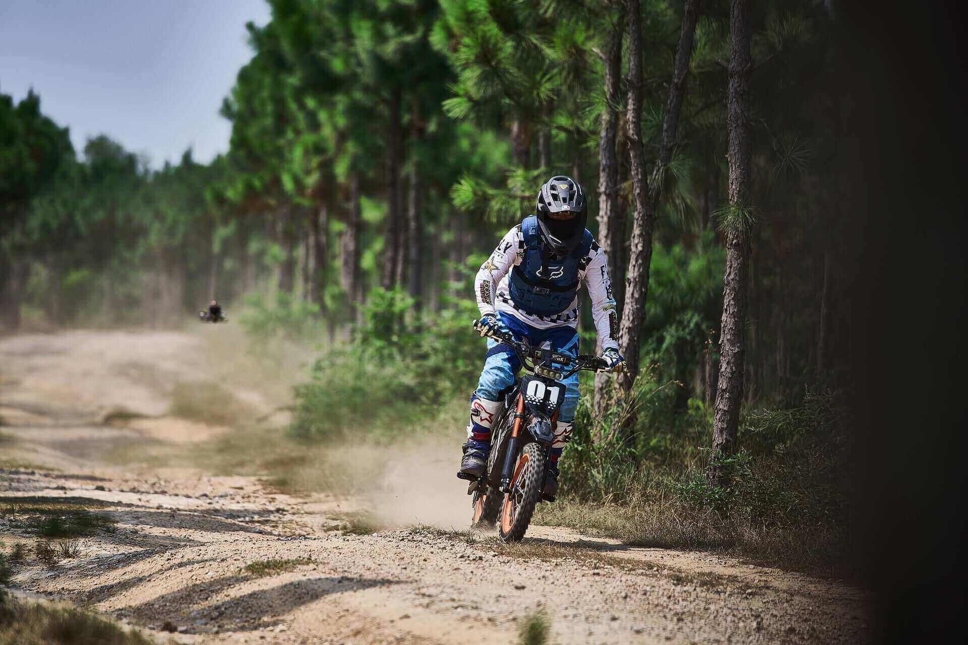 A biker racing on an off-road electric dirt bike in a forested trail, featured in The Ultimate Guide to 2026 Off-Road Electric Dirt Biking Evoltrix.